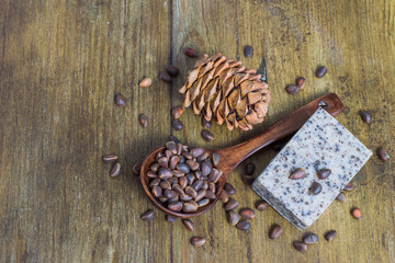 A piece of natural handmade soap, cedar cone and nuts on an old wooden background. 