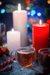 A couple of burning candles and glass cups of tea. Still life composition with christmass decoration on rustic background 4