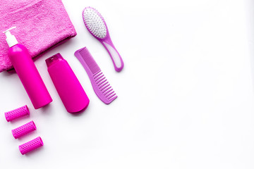 Basic hair care in bathroom. Comb, shampoo, spray, curlers, towel on white background top view copyspace