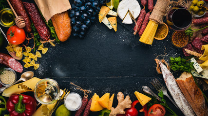 Assorted cheeses, sausages, wines, traditional spices and fresh vegetables on a wooden background. Cheese brie, blue cheese, gorgonzola, fuete, salami. Italian and Spanish Cuisine. Free space.