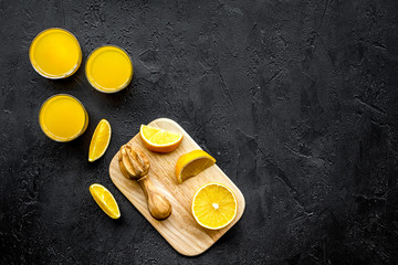 Squeeze juice from oranges. Juicer and slices of oranges on black background top view copyspace