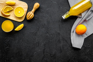 Squeeze juice from oranges. Juicer, slices of oranges, beverage in glass and bottle on black...