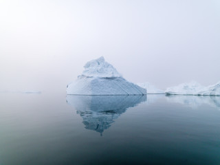 Fototapeta na wymiar Icebergs in foggy day on Arctic Ocean in Greenland
