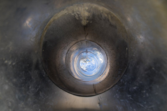 inside tube or pipe of great metal slide in playground with light at the end of tunnel or hole
