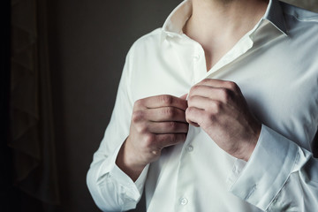 businessman dresses white shirt, male hands closeup,groom getting ready in the morning before wedding ceremony