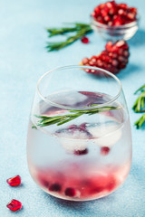 Summer refreshing detox pomegranate rosemary drink on light blue background. Selective focus, copy space. 