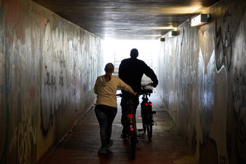 A man and a woman with bicycles walk along the underground passage