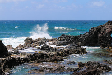 Fototapeta na wymiar blue pacific ocean breaking over black lava rock on maui north coast