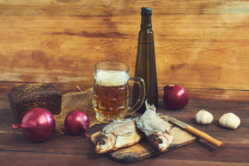Smoked fish, rye bread, garlic and glass of beer on a wooden background