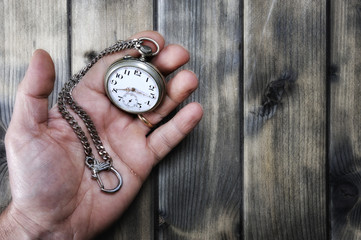 Adult man holding an antique pocket watch in his hand
