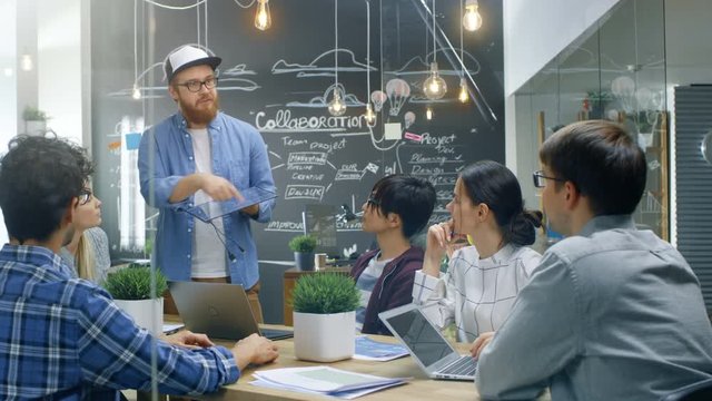 Charismatic Team Leader Talks with His Team of Progressive Engineers about Renewable Energy, He's Holding Extra Efficient Prototype of the Solar Panel. 