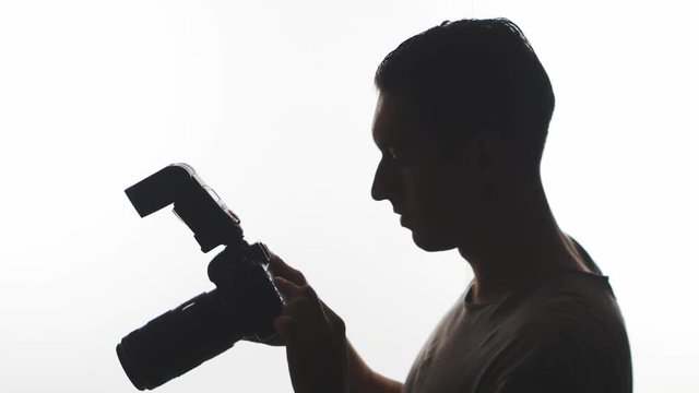Photographer Silhouette close-up. Young man takes pictures with DSLR camera isolated on white background