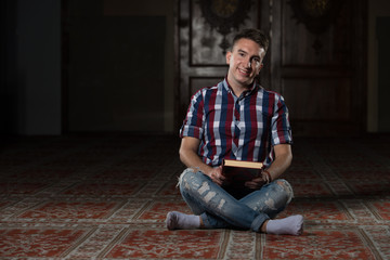 Young Muslim Guy Reading The Koran