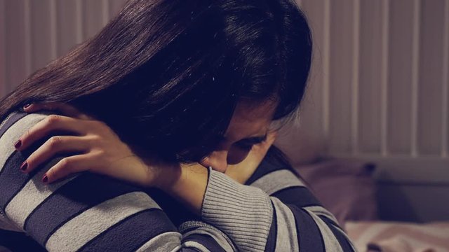 Hispanic female teenager in bedroom crying sad closeup