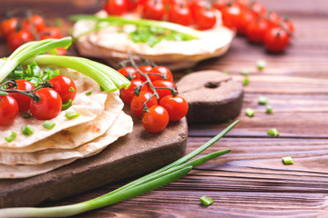 Indian chapati, green onion, cherry tomato.  Horizontal view, flatlay.