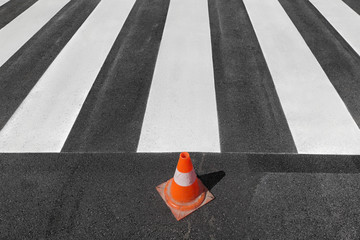 Fresh painted  pedestrian crosswalk at a street with traffic cone