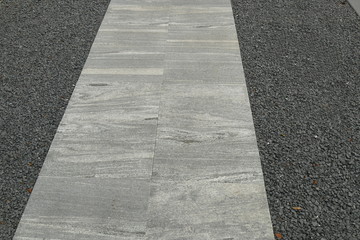 Weg aus marmorierten Platten in einem Schotterbeet, als gestalterisches Element