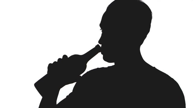 silhouette of young man drinks alcohol from a bottle isolated on white background