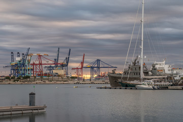 Fototapeta na wymiar shipping, maritime logistics port harbor cranes working loading transport ships, twilight reflection in water