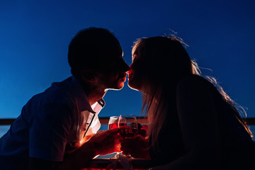 Silhouette of a couple who kisses on an evening date