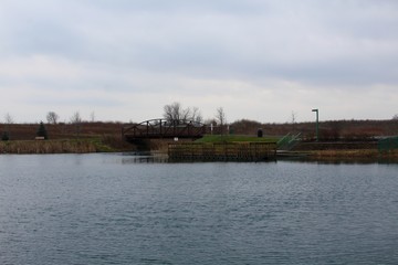 A view of the dock at the lake in the park on a cloudy day.