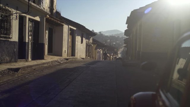 old red car parking on colonial street, motion shot passing motorbike reflecting in car windows, ancient town San Cristobal de las Casas