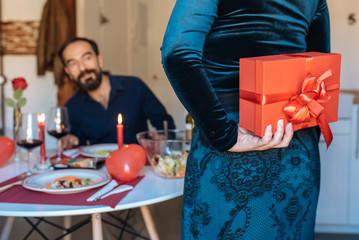 Mature couple having a romantic dinner at home for valentine’s day with surprise gift .