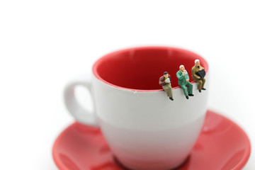 Miniatures people : sitting on a cup of coffee using as background business concept.