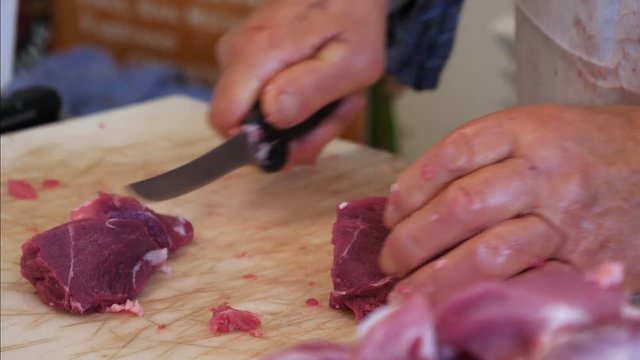 Butcher cutting pork meat on the table. Slow moton, pan shot. 