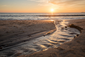 Sunset over the pacific Ocean as birds gather at a river outlet