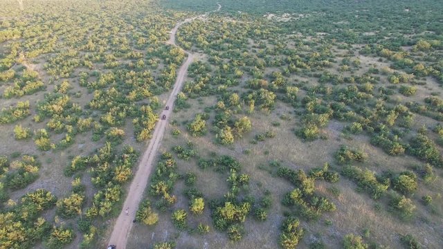 Drone shot of dune buggies driving offroad on a dirt road in nature