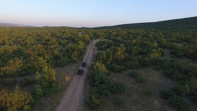 Drone shot of dune buggies driving offroad on a dirt road