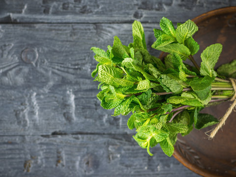 A bundle of mint in a clay bowl on a wooden table. The concept of healthy eating. The view from the top.