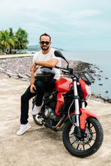 Fototapeta na wymiar Man sitting on his motorbike, holding helmet on sea background