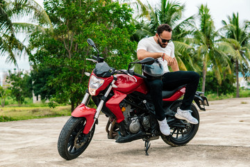 Fototapeta na wymiar Man sitting on his motorbike on palm background