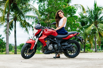 Fototapeta na wymiar Woman sitting on her motorcycle on palm background