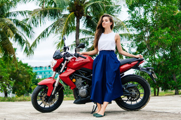 Obraz na płótnie Canvas Woman standng near her motorcycle on palm background