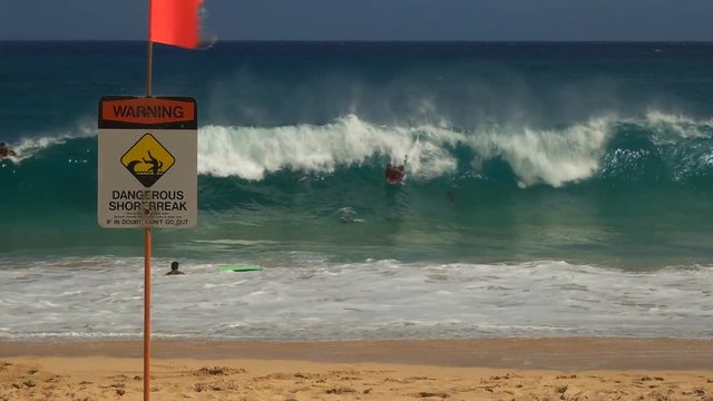 slow motion shot of a bodyboard surfers at the notoriously dangerous sandy beach, hawaii