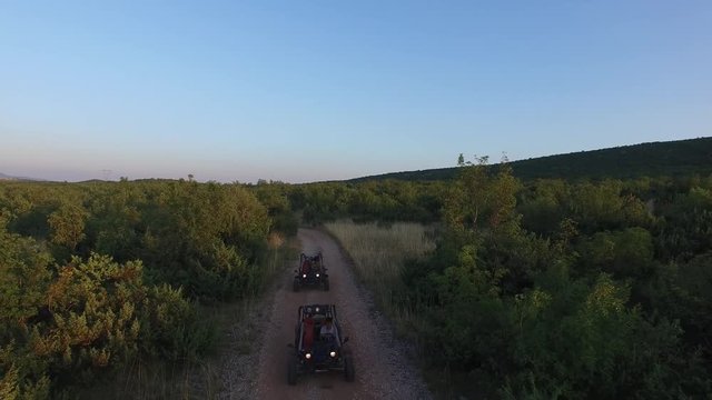 Drone shot of dune buggies driving on offroad on a dirt road together