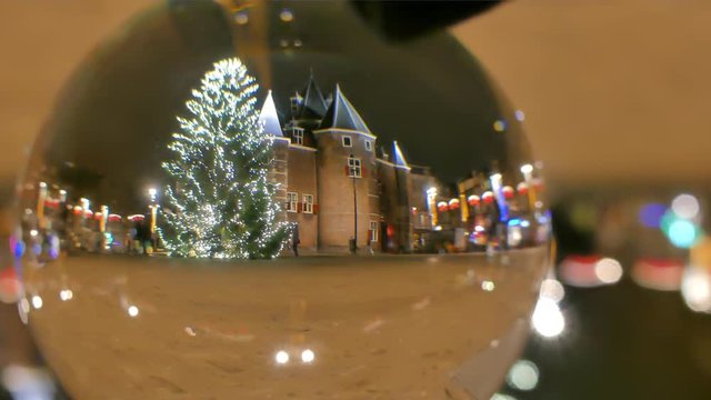 Big decorated Christmas tree in the evening, view through the glass ball. Amsterdam, Netherlands