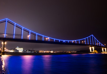Multicolored bridge over the river at night