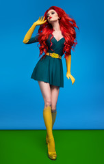 Beautiful woman in green superhero costume posing at camera on blue and green background