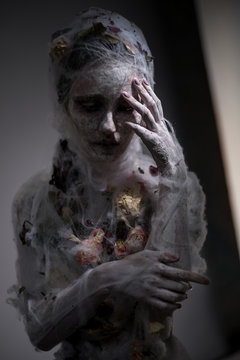 Portrait of sad woman in white veil with web posing at camera