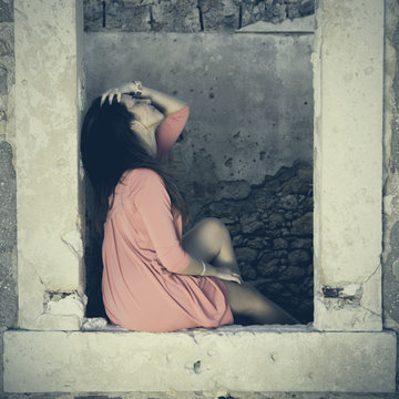 Close up of a 18Y old Girl Sitting in a Window of a Ruined House (location: Plemmirio Natural Park, Siracusa in Sicily)