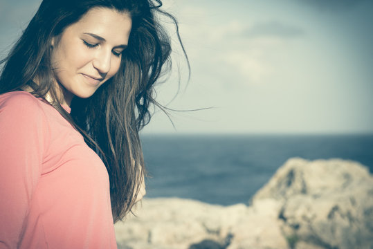Close up of a 18Y old girl in a rural location, sea at the background. Location: Plemmirio , Siracusa, in Sicily. 