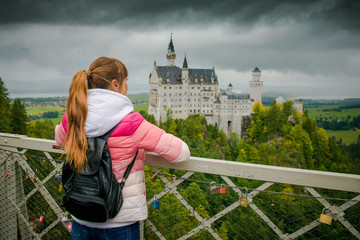 Girl tourist and castle Neuschweißen. The most famous German castle in gloomy foggy weather. 
