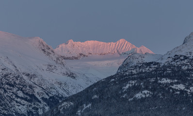 Snow topped mountain with sunset lights on the top of the mountain