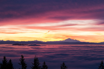 Low clouds moving like ocean wave with Mountain Baker in the background at sunrise in Vancouver, BC