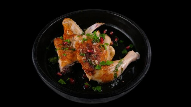 Roasted Chicken legs and wings, served with garnet seeds and spices in clay dish, transparent or black background