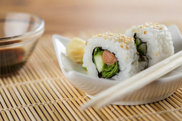 Zwei California Inside Out Sushi mit Lachs, Rucola und Gurke mit Sojasauce und Stäbchen